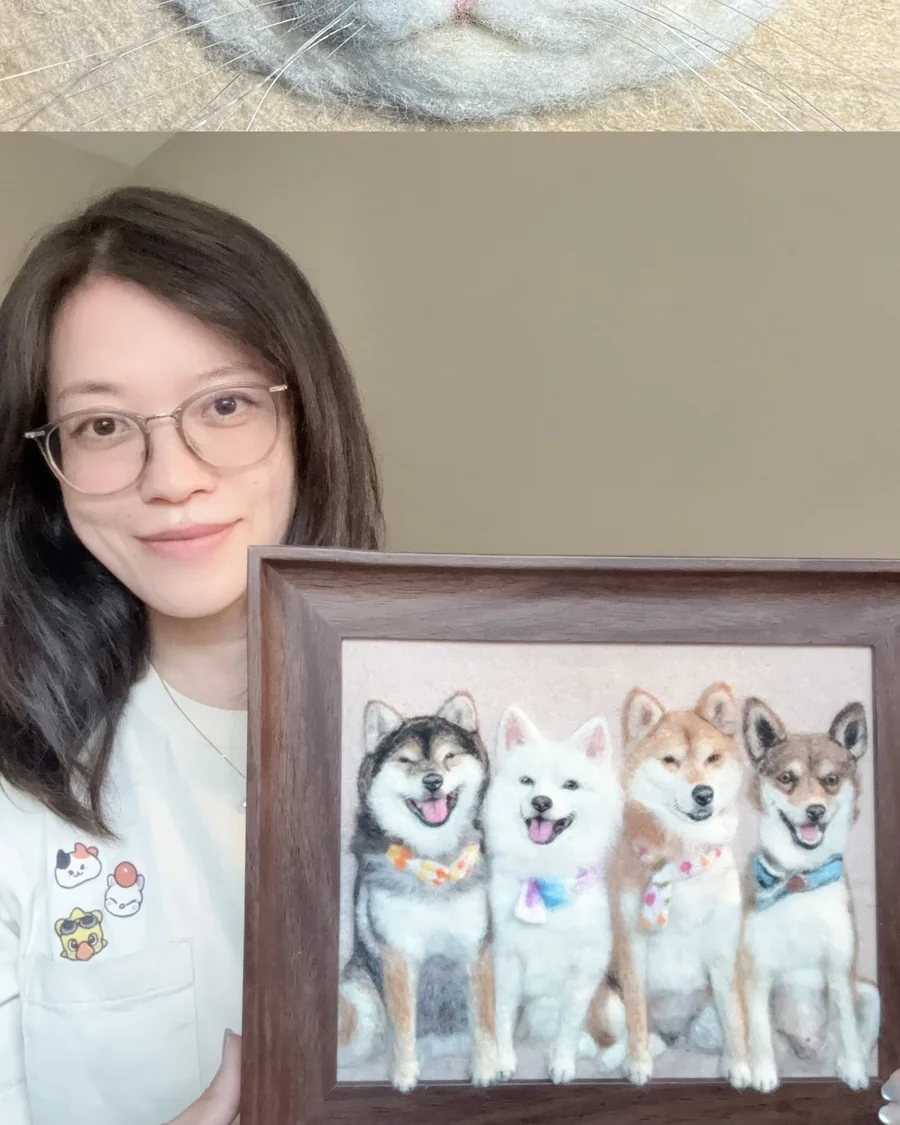 Emily holding a framed needle felted portrait of four shiba inus in bandanas